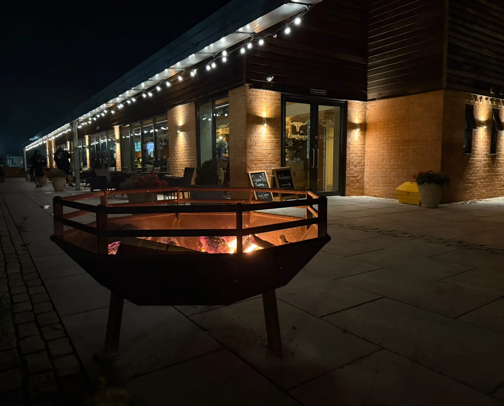 The Longhorn glowing after dark — fire pit lit and string lights over the terrace