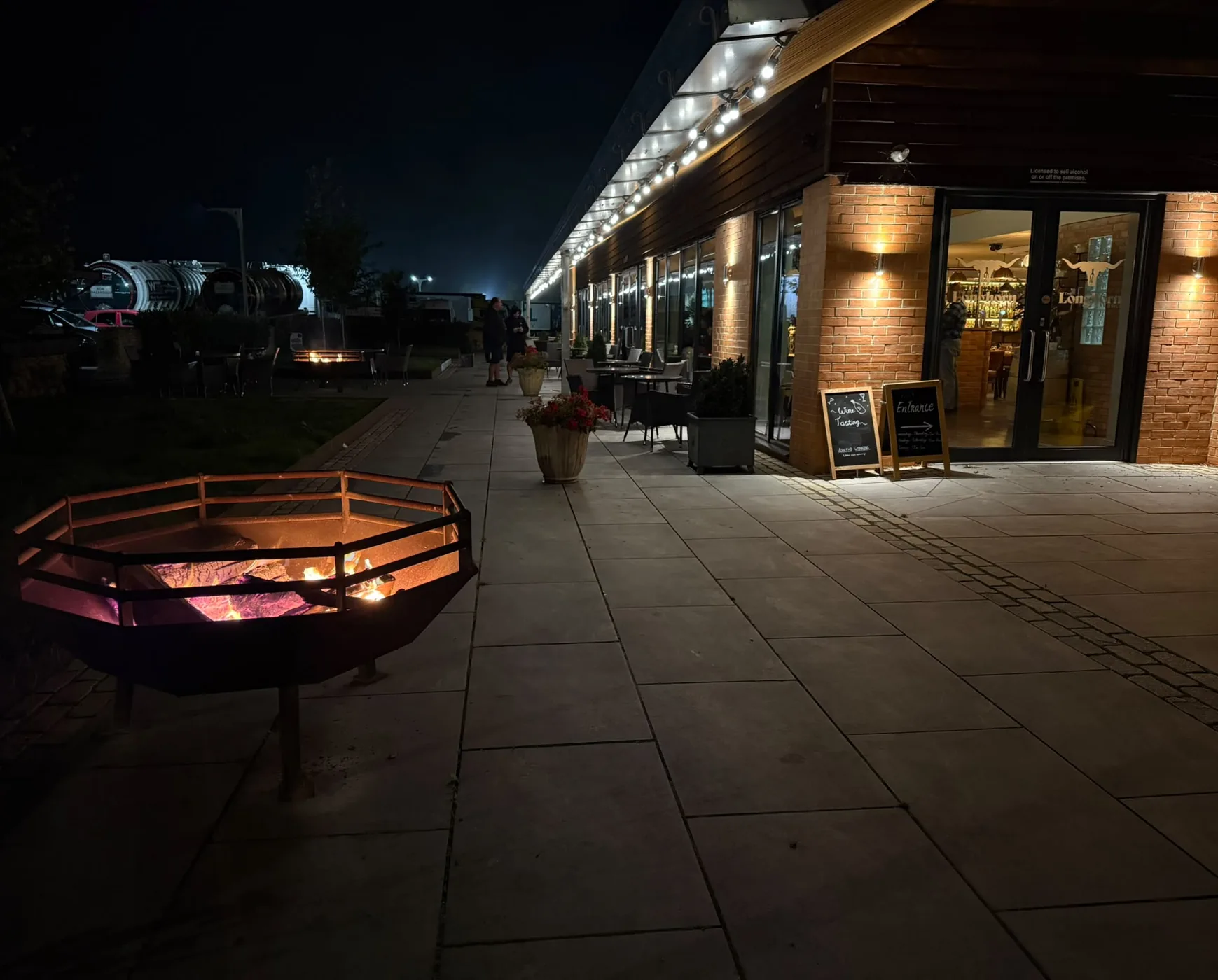 The Longhorn's entrance glowing after dark, string lights over the terrace and fire pit lit out front